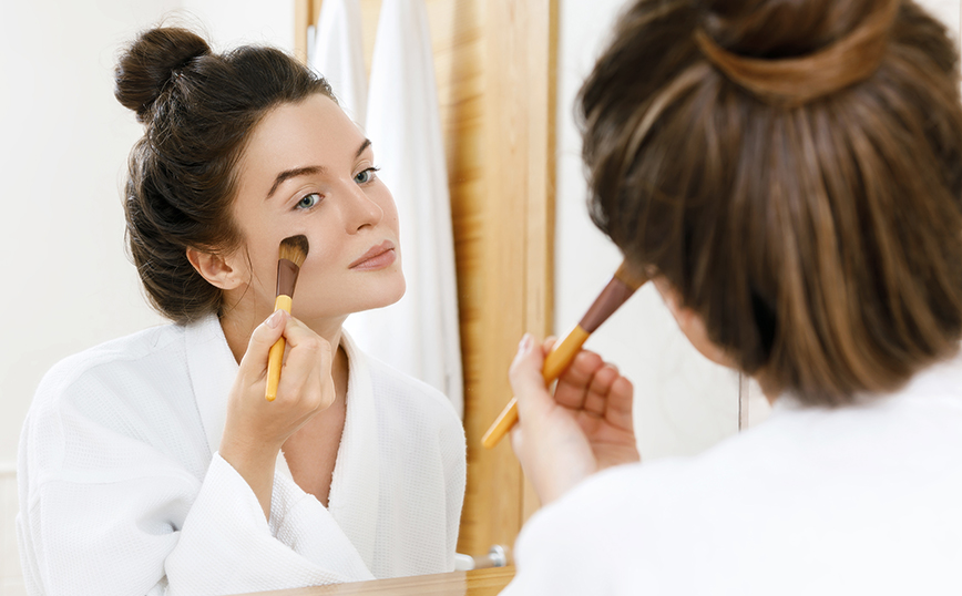 Νεαρή γυναίκα εφαρμόζει το foundation της Νεαρή γυναίκα εφαρμόζει το foundation της