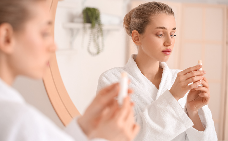 Νεαρή γυναίκα κρατάει βάλσαμο χειλιών Νεαρή γυναίκα κρατάει βάλσαμο χειλιών