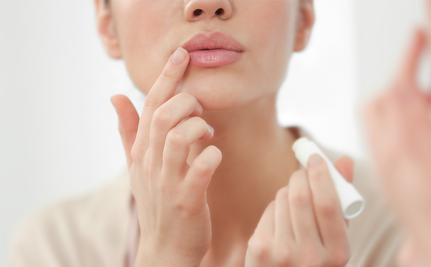 Γυναίκα βάζει στα χείλη της βάλσαμο χειλιών Γυναίκα βάζει στα χείλη της βάλσαμο χειλιών