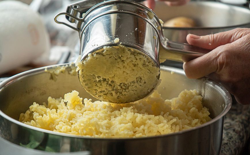 Γυναίκα τρίβει πατάτες για πουρέ Γυναίκα τρίβει πατάτες για πουρέ