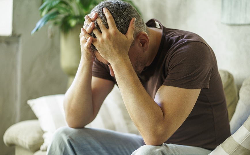 Άντρας στενοχωρημένος κάθεται στον καναπέ Άντρας στενοχωρημένος κάθεται στον καναπέ