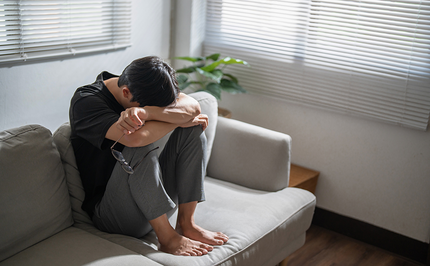 Άντρας στενοχωρημένος κάθεται στον καναπέ Άντρας στενοχωρημένος κάθεται στον καναπέ