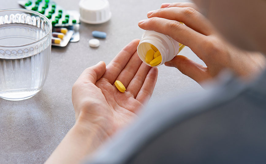 Γυναίκα κρατάει μπουκαλάκι με χάπια Γυναίκα κρατάει μπουκαλάκι με χάπια