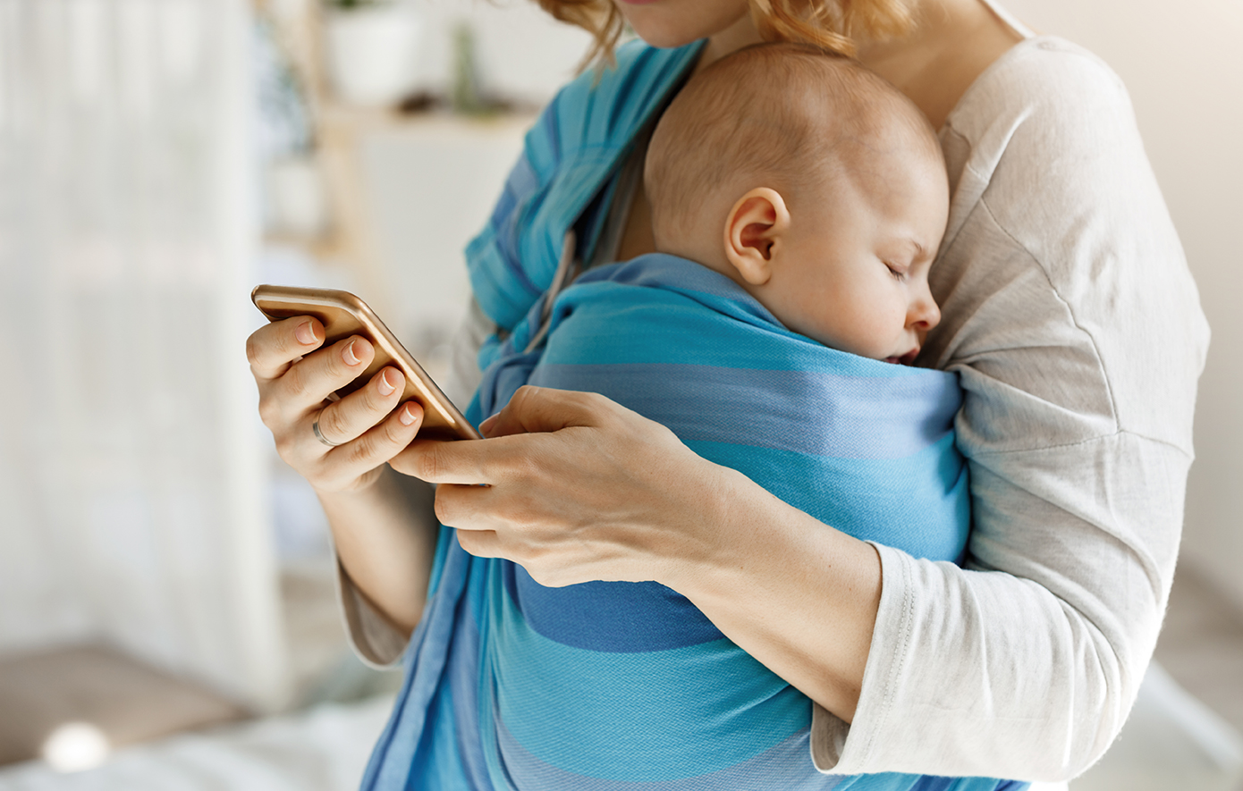 Μητέρα κρατάει μωρό και κοιτάει το τηλέφωνο της Μητέρα κρατάει μωρό και κοιτάει το τηλέφωνο της