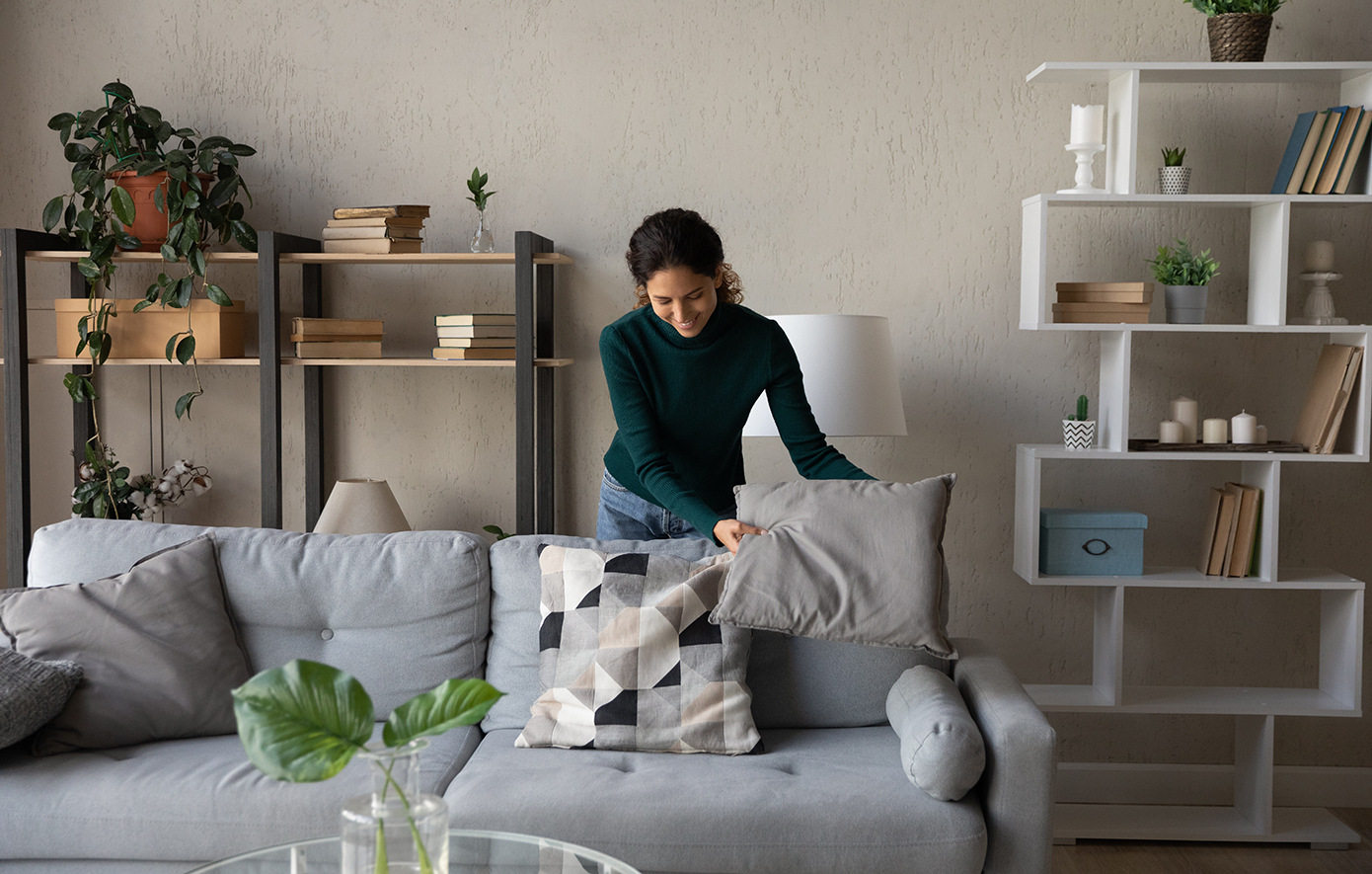 Γυναίκα τακτοποιεί τα μαξιλάρια του καναπέ