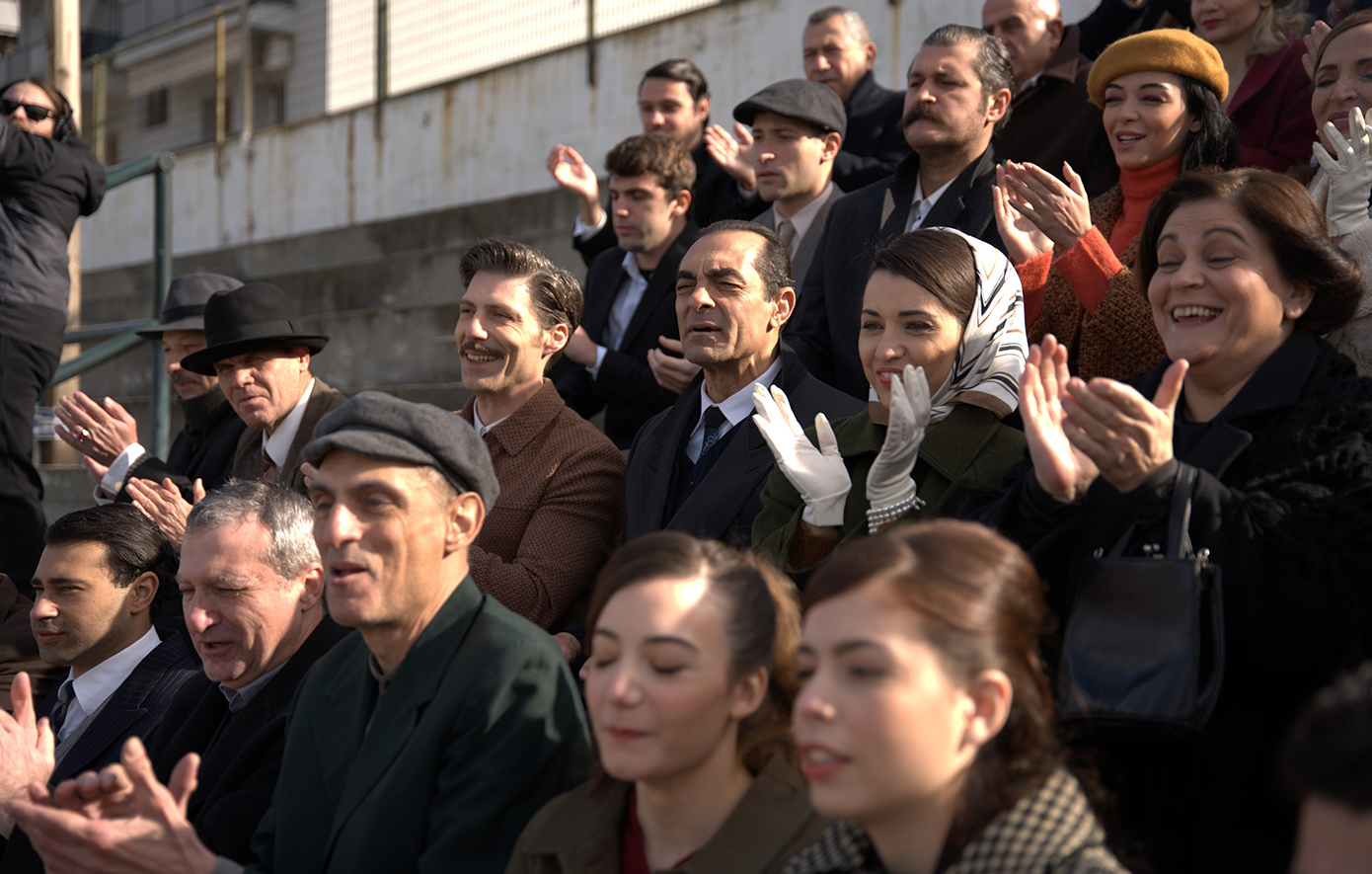 Η μεγάλη σειρά του Alpha, «Porto Leone: Στη γειτονιά με τα κόκκινα φανάρια», που έχει κατακτήσει το κοινό, μάς ταξιδεύει στον Πειραιά του 1964-65, σε μια εποχή που η ζωή, τα όνειρα και οι αγώνες είχαν χρώμα κόκκινο και λευκό.