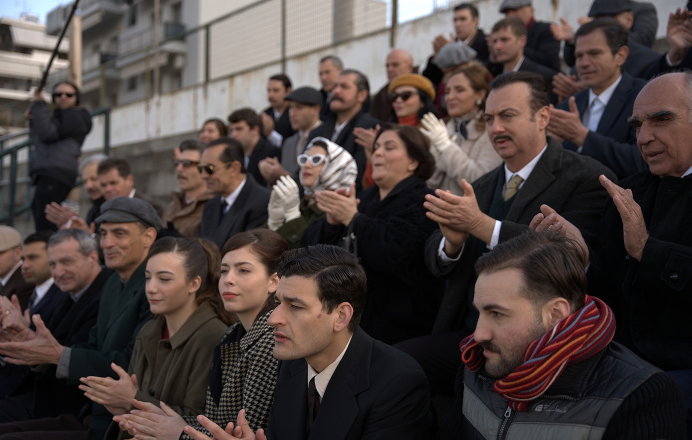 Η μεγάλη σειρά του Alpha, «Porto Leone: Στη γειτονιά με τα κόκκινα φανάρια», που έχει κατακτήσει το κοινό, μάς ταξιδεύει στον Πειραιά του 1964-65, σε μια εποχή που η ζωή, τα όνειρα και οι αγώνες είχαν χρώμα κόκκινο και λευκό.