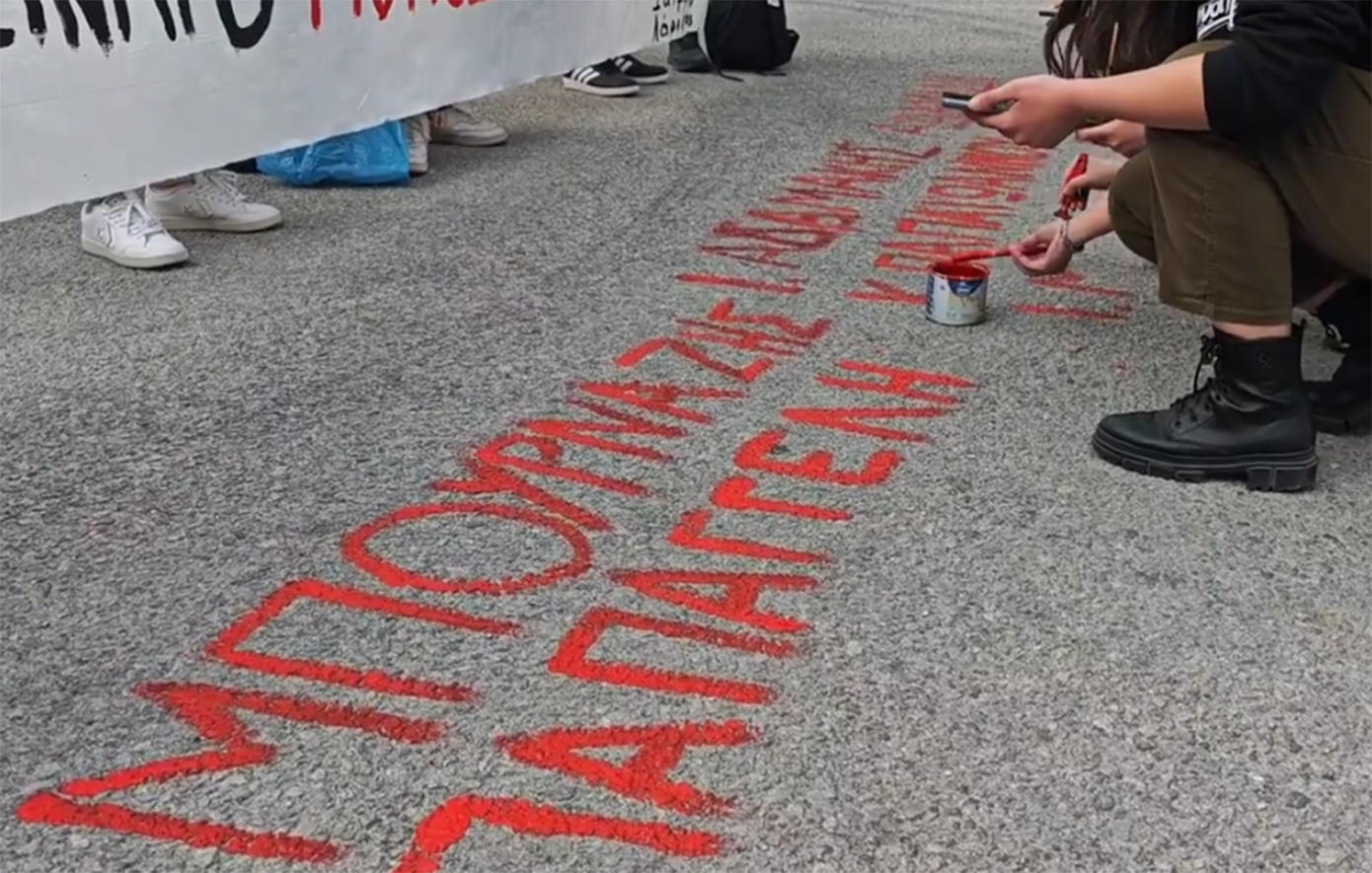 Διαδηλωτές βάφουν με μπογιά τα ονόματα των θυμάτων των Τεμπών απέναντι από τον χώρο διεξαγωγής της δίκης στη Λάρισα