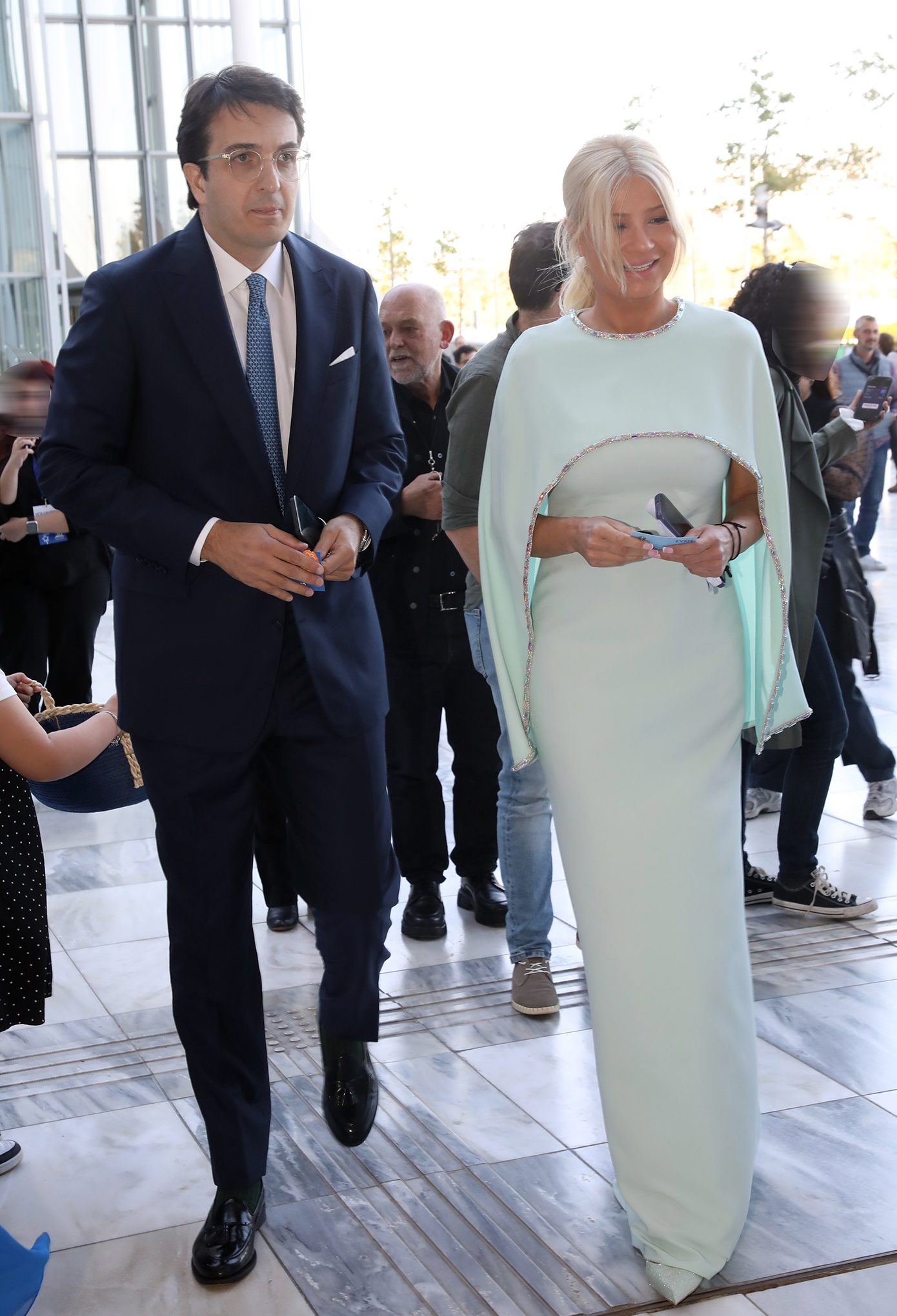 Η Φαίη Σκορδά με μάξι φόρεμα σε απόχρωση ice blue και ενσωματωμένη κάπα με στρας, δίπλα στον Αλέξανδρο Αθανασιάδη σε επίσημη εκδήλωση