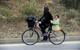 Migrants from Syria ride their bicycles near the Greek border in Macedonia June 17, 2015.  Hungary announced plans on Wednesday to build a four-metre-high fence along its border with Serbia to stem the flow of illegal migrants. Tens of thousands of migrants enter Europe through the Balkans from the Middle East and Africa. REUTERS/Ognen Teofilovski