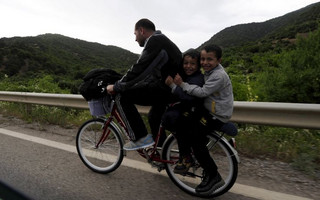 Migrants from Syria ride their bicycles near the Greek border in Macedonia June 17, 2015.  Hungary announced plans on Wednesday to build a four-metre-high fence along its border with Serbia to stem the flow of illegal migrants. Several thousand migrants are daily crossing the Balkans towards Hungary on their way to other European Union countries. REUTERS/Ognen Teofilovski