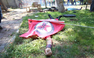 A victim, with a flag of the left-wing Federation of Socialist Youth Associations covering him, lies on the ground following an explosion in Suruc