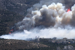 A firefighting helicopter drops water at a raging wildfire at the Kareas suburb, east of Athens, Greece July 17, 2015. Dozens of Athens residents fled their homes on Friday as wildfires fanned by strong winds and high temperatures burned through woodland around the Greek capital, sending clouds of smoke billowing over the city.    REUTERS/Alkis Konstantinidis