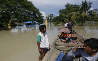 A boat man (L) stands on the flooded roof of a home next to the media boat in a flooded village at Kalay township at Sagaing division, August 2, 2015. Storms and floods have so far killed 21 people, with water levels as high as 2.5 metres in Sagaing and 4.5 metres in western Rakhine state, according to the government, which on Friday declared four regions disaster zones. REUTERS/Soe Zeya Tun