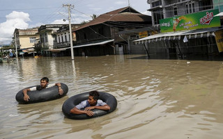Men wade along a flooded street at Kalay township at Sagaing division, August 2, 2015. Storms and floods have so far killed 21 people, with water levels as high as 2.5 metres in Sagaing and 4.5 metres in western Rakhine state, according to the government, which on Friday declared four regions disaster zones. REUTERS/Soe Zeya Tun