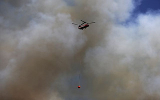A firefighting helicopter carries a load of water through the smoke during the Rocky Fire near Lower Lake, California August 3, 2015. The blaze, which has scorched about 60,000 acres (24,281 hectares) east of Lower Lake, a town about 110 miles (180 km) north of San Francisco, was the fiercest of 20 large fires being battled by 9,000 firefighters across the state, officials said. REUTERS/Stephen Lam