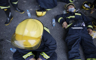 Firefighters take a break after trying to put fire down at the explosion site in Binhai new district in Tianjin, China August 13, 2015. The death toll from two huge explosions that tore through an industrial area in the northeastern Chinese port of Tianjin more than doubled to 44, the official Xinhua news agency said on Thursday.  REUTERS/Damir Sagolj      TPX IMAGES OF THE DAY
