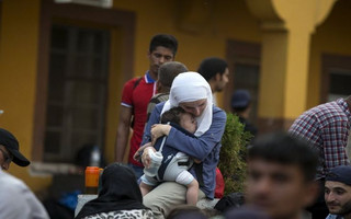 A migrant woman holds her child, as they wait for a train to arrive at Gevgelija train station in Macedonia, close to the border with Greece, August 14, 2015. In the past month, an estimated 30,000 refugees have passed through Macedonia, another step in their uncertain search for a better life in western Europe.  REUTERS/Stoyan Nenov