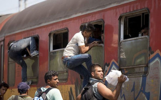 Migrants board a train through the windows at Gevgelija train station in Macedonia, close to the border with Greece, August 15, 2015. In the past month, an estimated 30,000 refugees have passed through Macedonia, another step in their uncertain search for a better life in western Europe.  REUTERS/Stoyan Nenov