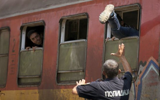 A policeman tries to stop a migrant from boarding a train through a window at Gevgelija train station in Macedonia, close to the border with Greece, August 15, 2015. In the past month, an estimated 30,000 refugees have passed through Macedonia, another step in their uncertain search for a better life in western Europe.  REUTERS/Stoyan Nenov       TPX IMAGES OF THE DAY