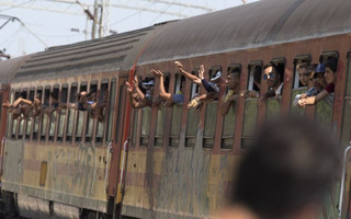 Migrants wave as their train leaves Gevgelija station in Macedonia, close to the border with Greece, August 15, 2015. In the past month, an estimated 30,000 refugees have passed through Macedonia, another step in their uncertain search for a better life in western Europe.  REUTERS/Stoyan Nenov