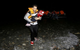 A Syrian refugee carries a child as they arrive at a beach on the Greek island of Kos after crossing a part of the Aegean sea from Turkey to Greece on a dinghy August 13, 2015. The United Nations refugee agency (UNHCR) called on Greece to take control of the "total chaos" on Mediterranean islands, where thousands of migrants have landed. About 124,000 have arrived this year by sea, many via Turkey, according to Vincent Cochetel, UNHCR director for Europe. REUTERS/Yannis Behrakis