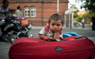 A migrant boy waits at his parents' suitcase as they leave the Berlin State Office for Health and Social Affairs with other newly arrived refugees who waited all day to apply for asylum in Berlin, August 10, 2015.  REUTERS/Stefanie Loos