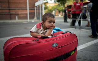 A migrant boy waits at his parents' suitcase as they leave the Berlin State Office for Health and Social Affairs with other newly arrived refugees who waited all day to apply for asylum in Berlin, August 10, 2015.  REUTERS/Stefanie Loos