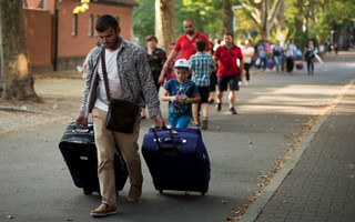 Migrants with bags leave the Berlin State Office for Health and Social Affairs with other newly arrived refugees who waited all day to apply for asylum in Berlin, August 10, 2015.  REUTERS/Stefanie Loos