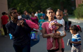 Migrants with bags leave the Berlin State Office for Health and Social Affairs with other newly arrived refugees who waited all day to apply for asylum in Berlin, August 10, 2015.  REUTERS/Stefanie Loos