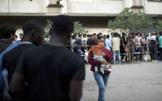 A newly arrived migrant carries her child as she waits among other migrants to apply for asylum at the State Office for Health and Social Affairs in Berlin, Germany August 10, 2015. REUTERS/Stefanie Loos