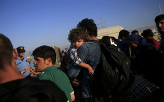 A Syrian child is carried by its father at the port of Kos following a rescue operation off the Greek island of Kos