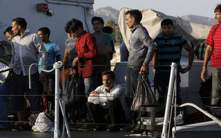 Migrants wait aboard an Italian coast guard vessel before disembarking at the port of Kos following a rescue operation off the Greek island of Kos