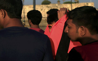 A migrant looks on as he removes his lifejacket at the port of Kos, following a rescue operation off the Greek island of Kos