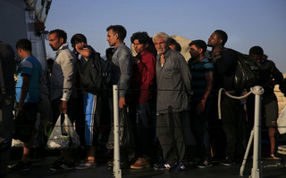 Migrants line up onboard an Italian coast guard vessel before disembarking at the port of Kos following a rescue operation off the Greek island of Kos