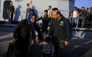 An Italian coast guard officer caresses a Syrian child at the port of Kos, following a rescue operation off the Greek island of Kos