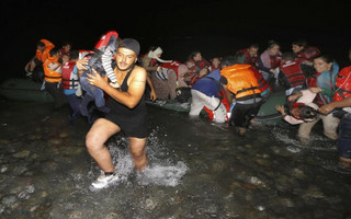 A Syrian refugee carries a child as they arrive at a beach on the Greek island of Kos after crossing a part of the Aegean sea from Turkey to Greece on a dinghy August 13, 2015. The United Nations refugee agency (UNHCR) called on Greece to take control of the "total chaos" on Mediterranean islands, where thousands of migrants have landed. About 124,000 have arrived this year by sea, many via Turkey, according to Vincent Cochetel, UNHCR director for Europe. REUTERS/Yannis Behrakis