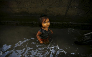 A girl walks through floodwaters caused by the heavy rainfall flowing from the swollen Bagmati River, which entered a slum in Kathmandu