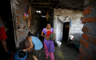 People salvage their belongings after floodwaters caused by the heavy rainfall flowing from the swollen Bagmati River entered their slum in Kathmandu