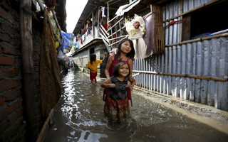 Children walk along an alley filled with floodwaters caused by heavy rainfall flowing from the swollen Bagmati River in a slum in Kathmandu