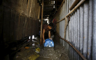 A man clears water from his shed after floodwaters caused by heavy rainfall flowing from the swollen Bagmati River entered the slum in Kathmandu