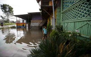 A boy walks outside houses filled with floodwaters flowing from the swollen Bagmati River caused by the heavy rainfall in Kathmandu