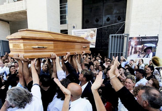 People carries the body of Vittorio Casamonica into a Roman Catholic basilica in a Rome suburb, where the funeral mass was celebrated, August 20, 2015. Casamonica, 65, the head of a notorious Rome crime family, was given a lavish funeral on Thursday, with a helicopter dropping red rose petals on mourners and a brass band playing the theme tune from the Godfather movie. Picture taken August 20, 2015. REUTERS/Stringer