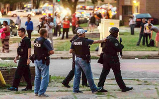 Police monitor the crowd as protesters gathered after a shooting incident in St. Louis