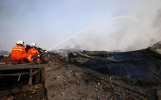 Firefighters wearing gas masks try to put out a fire at the site of Wednesday night's explosions in Binhai new district of Tianjin