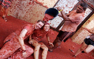 A reveler pours tomato pulp over a couple after the annual "Tomatina" (tomato fight) in Bunol, near Valencia
