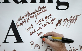 A women signs a memorial for journalists who died in a shooting outside of the offices of WDBJ7 in Roanoke, Virginia