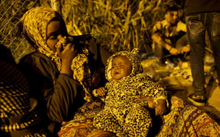 A migrant holds her baby as they wait to enter Hungary after the Hungarian police sealed the border with Serbia, near the village of Horgos, Serbia, September 14, 2015. REUTERS/Marko Djurica