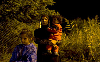 A migrant stands with her children as they wait to enter Hungary after the Hungarian police sealed the border with Serbia near the village of Horgos, Serbia, September 14, 2015. REUTERS/Marko Djurica