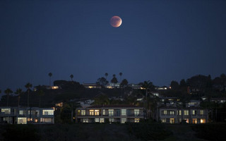 A blood moon rises behind hilltop residences in Solana Beach